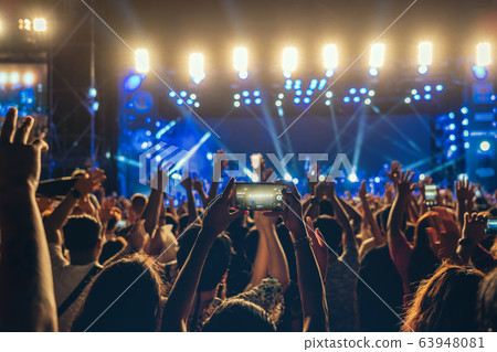 Concert crowd of Music fanclub hand using cellphone taking video record or Live stream with superstar songer, happy new year, christmas and festival concept Concert crowd of Music fanclub hand using cellphone taking video record or Live stream with superstar songer, happy new year, christmas and festival concept 63948081