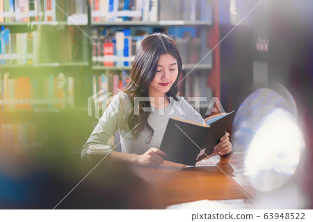 Asian young Student in casual suit reading the book with a cup of coffee in library of university or colleage on the wooden table over the book shelf background, Back to school concept Asian young Student in casual suit reading the book with a cup of coffee in library of university or colleage on the wooden table over the book shelf background, Back to school concept 63948522