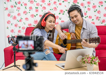 Asian Vlogger of married couple playing and sharing the music to attendee via mobile phone by social media channel,checking comment via laptop, camera taking video and live,vlog and Influencer concept Asian Vlogger of married couple playing and sharing the music to attendee via mobile phone by social media channel,checking comment via laptop, camera taking video and live,vlog and Influencer concept 63948534
