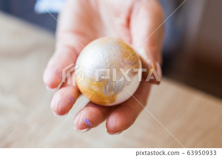 Holidays, handmade and creation concept - Girl draws on Easter egg, close-up. Holidays, handmade and creation concept - Girl draws on Easter egg, close-up. 63950933