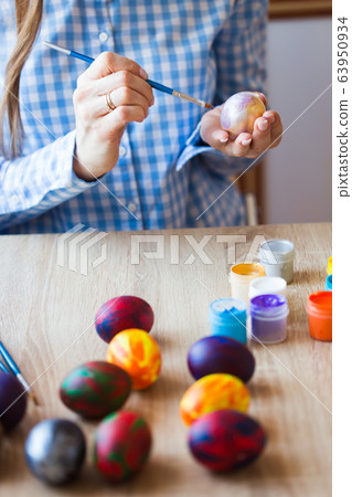Holidays, handmade and creation concept - Girl draws on Easter egg, close-up. Holidays, handmade and creation concept - Girl draws on Easter egg, close-up. 63950934