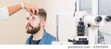 Medicine, health, ophthalmology concept - Ophthalmologist examines patient's eyes. 63950944