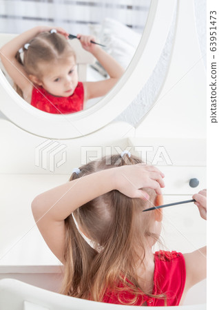 girl in a red dress combing herself in front of a 63951473