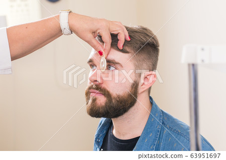 Medicine, health, ophthalmology concept - Ophthalmologist examines patient's eyes. Medicine, health, ophthalmology concept - Ophthalmologist examines patient's eyes. 63951697
