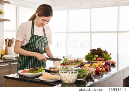Woman making a dish of vegetable salad. 63955644