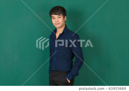 Young Asian man standing at green wall. Young Asian man standing at green wall. 63955669