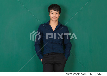 Young Asian man standing at green wall. Young Asian man standing at green wall. 63955670