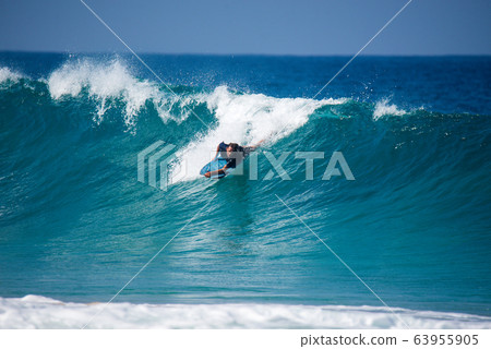 A surfer who surfers a big wave 63955905