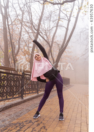 Muslim sportswoman exercising in the park and doing bends stock photo 63957630