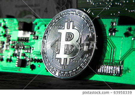 Silver bitcoin coin in front of computer motherboard, cryptocurrency mining and investing concept Silver bitcoin coin in front of computer motherboard, cryptocurrency mining and investing concept 63958339