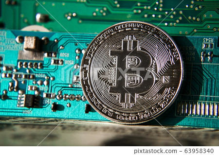 Silver bitcoin coin in front of computer motherboard, cryptocurrency mining and investing concept Silver bitcoin coin in front of computer motherboard, cryptocurrency mining and investing concept 63958340