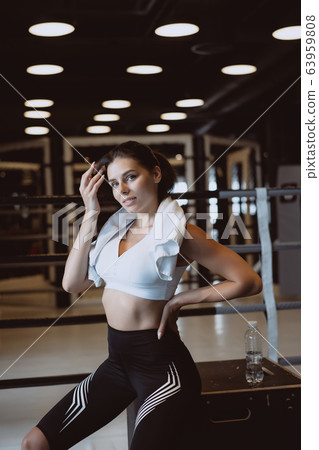 Smiling fit girl holding towel and taking rest in gym. Smiling fit girl holding towel and taking rest in gym. 63959808