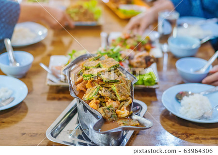 Group of female friends enjoy eating with acacia pennata omelette sour soup in fish shape hot pot in the restaurant. Selective focus. Group of female friends enjoy eating with acacia pennata omelette sour soup in fish shape hot pot in the restaurant. Selective focus. 63964306