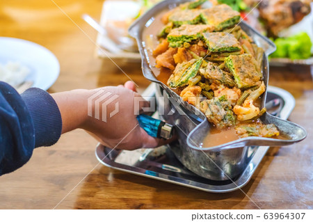 Group of female friends enjoy eating with acacia pennata omelette sour soup in fish shape hot pot in the restaurant. Selective focus. Group of female friends enjoy eating with acacia pennata omelette sour soup in fish shape hot pot in the restaurant. Selective focus. 63964307
