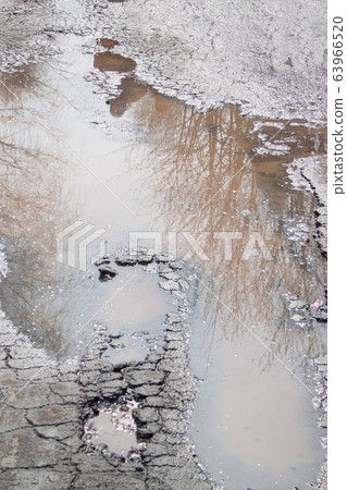 Bad asphalted road. Big pothole filled with water. 63966520