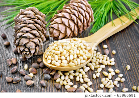 Cedar nuts peeled in spoon on wooden board 63966691