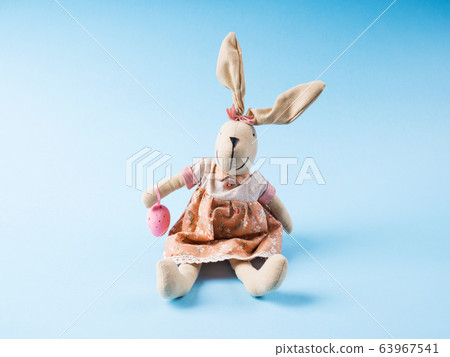 Easter bunny with pink egg on blue backdrop Easter bunny with pink egg on blue backdrop 63967541