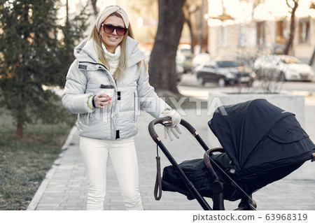 Stylish woman walking in a city with carriage 63968319
