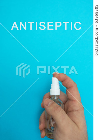 Hands with antisentic disinfector on a blue background and with the text ANTISEPTIC, top view, flat Hands with antisentic disinfector on a blue background and with the text ANTISEPTIC, top view, flat 63968885
