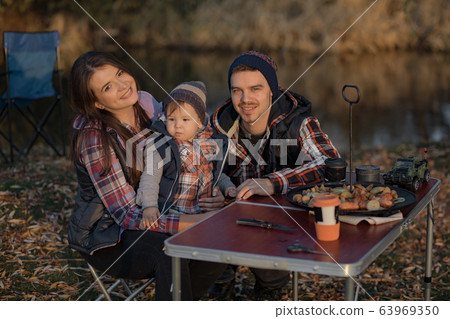 Cute family sitting on a picnic in a forest Cute family sitting on a picnic in a forest 63969350