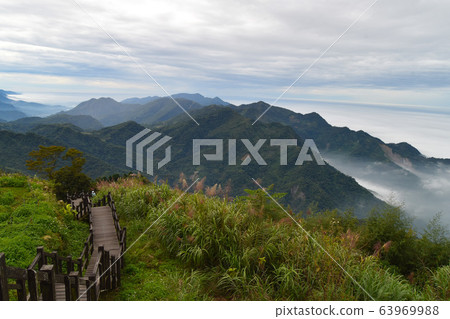 靛藍的藍天,綠樹,白色,茂密的多雲山脈。 靛藍的藍天,綠樹,白色,茂密的多雲山脈。 63969988