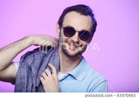 Studio shot of handsome man wearing sunglasses over pink background. Studio shot of handsome man wearing sunglasses over pink background. 63970063