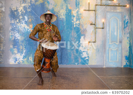 African man in traditional clothes playing djembe drum 63970202