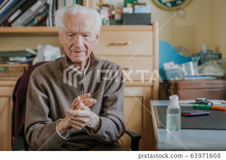 Senior disinfects hands with antibacterial gel 63971608