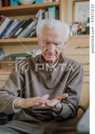 Senior disinfects hands with antibacterial gel Senior disinfects hands with antibacterial gel 63971610