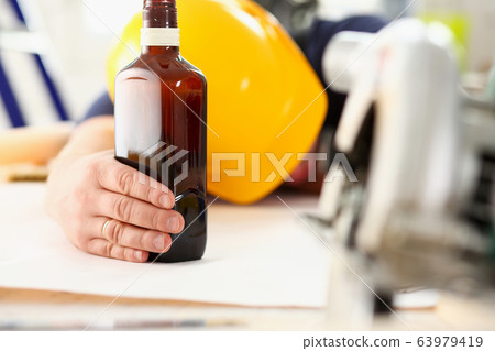 Arm of drunken worker in yellow helmet 63979419