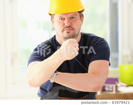 Smiling funny worker in yellow helmet posing Smiling funny worker in yellow helmet posing 63979421