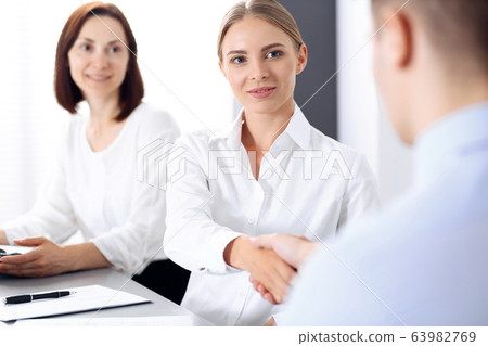 Business handshake by blonde woman and her partner at meeting. Concept of success and agreement Business handshake by blonde woman and her partner at meeting. Concept of success and agreement 63982769
