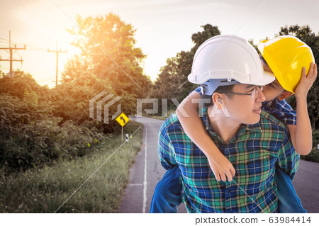 Father builder is carrying his son in country road Father builder is carrying his son in country road 63984414