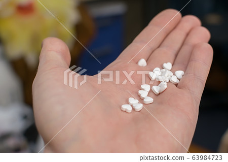 in the hand, on the palm of the person cute white pills with hearts 63984723