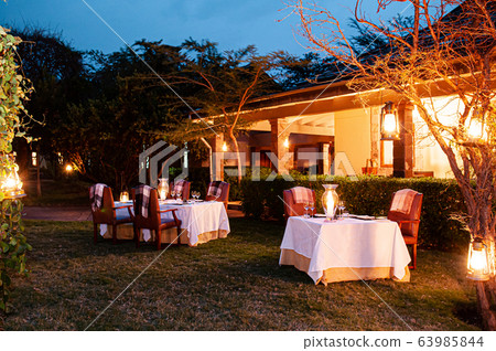 Luxury African Safari lodge outdoor dining on grass lawn 63985844