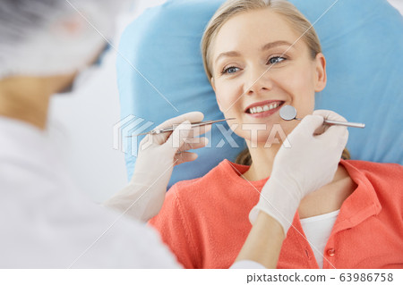 Smiling caucasian woman is being examined by dentist at dental clinic. Healthy teeth and medicine, stomatology concept 63986758