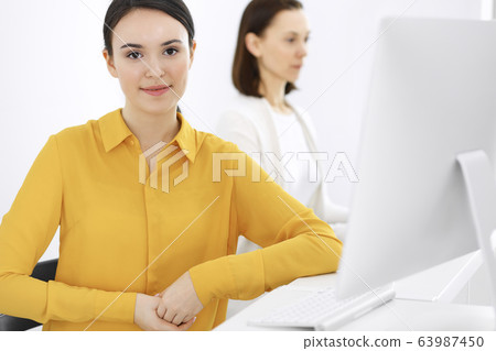 Businesswoman in mustard colored blouse looking at camera at office, headshot Businesswoman in mustard colored blouse looking at camera at office, headshot 63987450