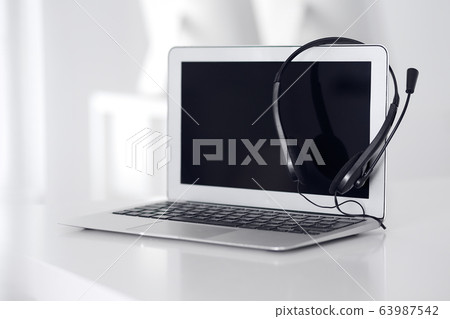 Call center and communication support, customer service help desk. VOIP headset on laptop computer Call center and communication support, customer service help desk. VOIP headset on laptop computer 63987542