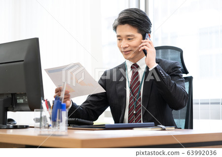 Manager talking while looking at documents in the office Manager talking while looking at documents in the office 63992036