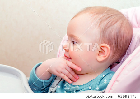 Feeding cute baby girl in pram with spoon Feeding cute baby girl in pram with spoon 63992473