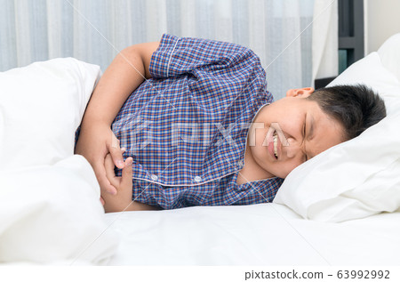 asian child suffering from stomachache and lying asian child suffering from stomachache and lying 63992992