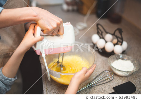 Mother and daughter making cake at home 63993483