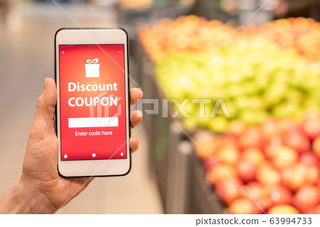 Hand of contemporary mature female buyer showing you online discount coupon Hand of contemporary mature female buyer showing you online discount coupon 63994733