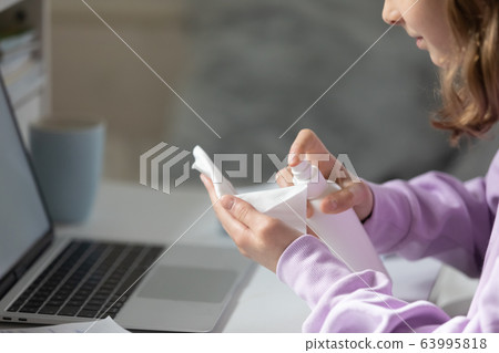 Young teen girl applying antibacterial spray liquid on napkin. Young teen girl applying antibacterial spray liquid on napkin. 63995818