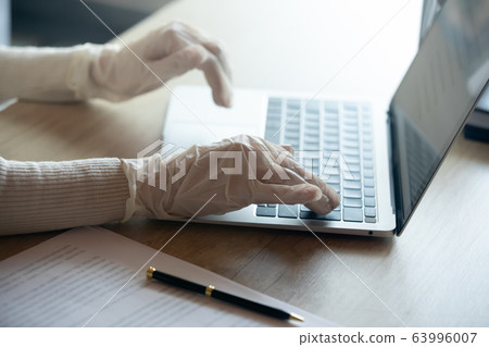 Young cautious businesswoman working on computer in gloves. Young cautious businesswoman working on computer in gloves. 63996007