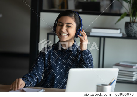 Happy young indian girl listening to music in headphones. Happy young indian girl listening to music in headphones. 63996076
