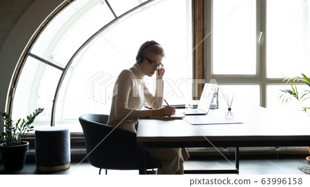 Focused leader sitting at table, holding online meeting with coworkers. Focused leader sitting at table, holding online meeting with coworkers. 63996158
