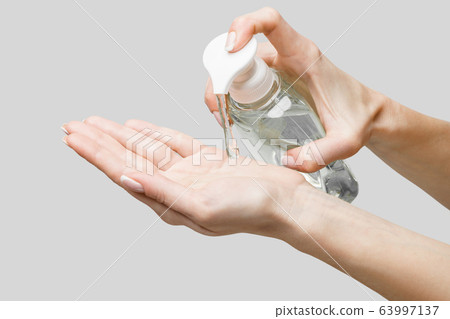 Female hands using hand sanitizer gel or liquid soap dispenser over light grey background 63997137