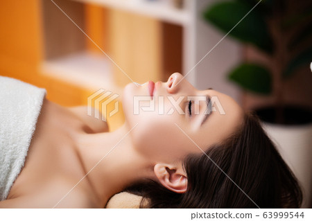 Pretty woman applying face mask at spa salon 63999544