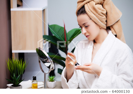Pretty girl doing cosmetic procedures at home in front of mirror Pretty girl doing cosmetic procedures at home in front of mirror 64000130